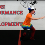 A clown on a unicycle with a red nose providing tips on performance and act development. Learn from the pros with our circus skills education pack and YouTube channel