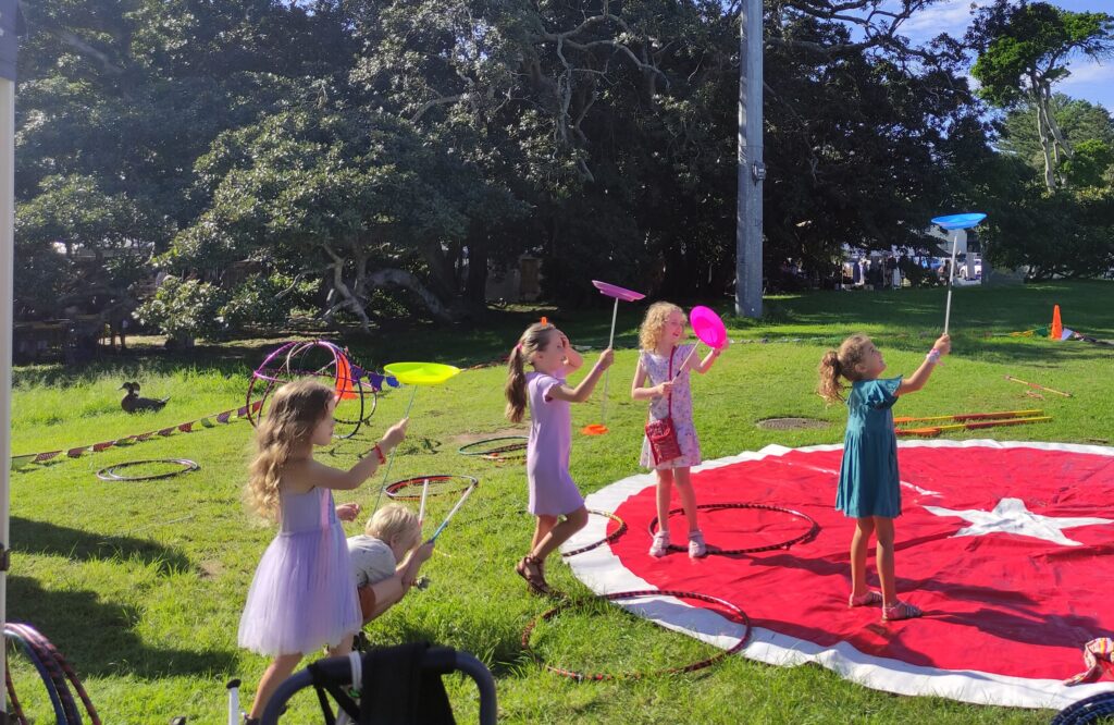Plate spinning is so much fun with friends! A group of children are spinning plates in the park. At active fest you will be able to learn how to spin plates in the Roundabout Circus play space.