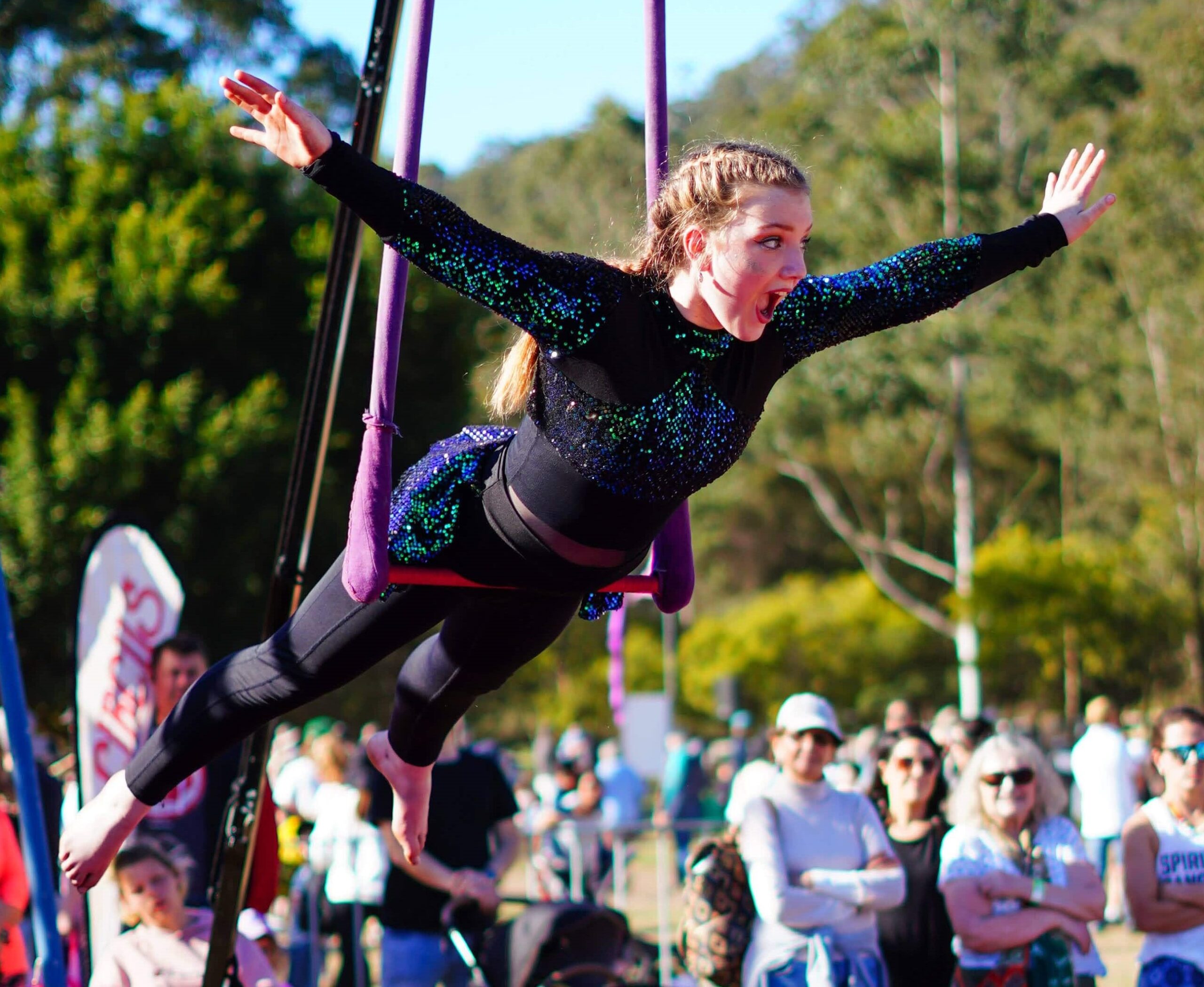 An awe-inspiring shot of a young artist mid-air during a trapeze act, displaying grace and strength.