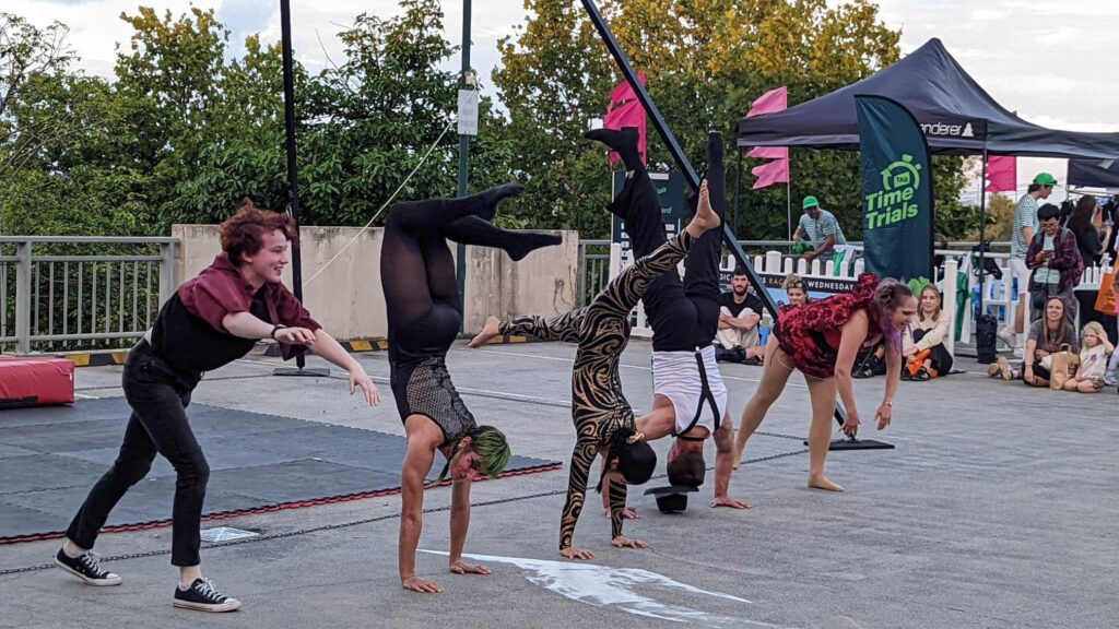 Five people doing a handstand in a line outdoors at a performance event